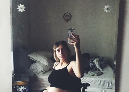 Rebekah holds her phone up to her bedroom mirror. The only light in the room comes from a window to her left. Her pregnant tummy pops out under her black tank top. Her face is anxious, heavy, burdened. Oh, and below the mirror, her bedroom dresser is cluttered, as always.