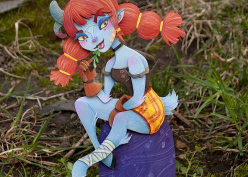 Cut paper Satyr sitting on a rock chewing hay.